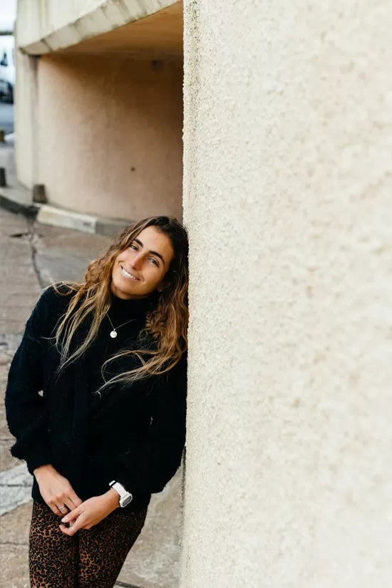 Ana leaning against a wall, smiling into the camera